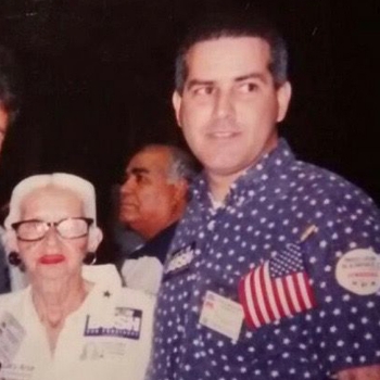 Al Santos con camisa azul de lunares y bandera americana