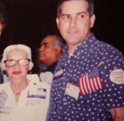 Al Santos con camisa azul de lunares y bandera americana