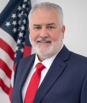 Al Santos headshot in front of an American flag