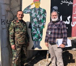 Al Santos standing with a military member in front of a painting of a soldier saluting